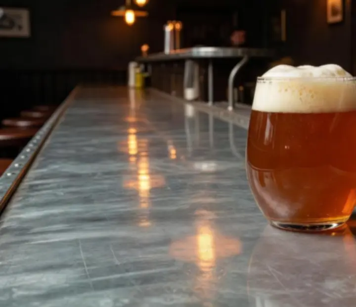Cerveza artesanal servida sobre barra metálica junto a copas.