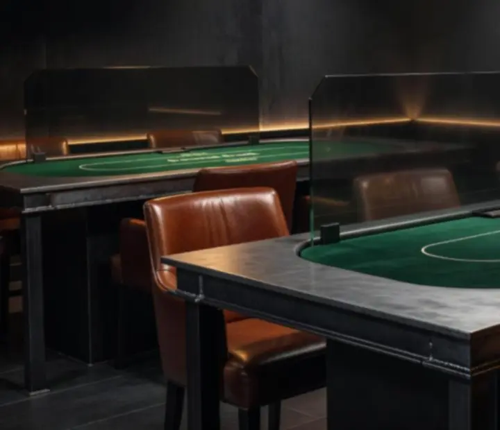 Mesas de poker con acabado industrial, iluminación cálida y asientos de cuero.